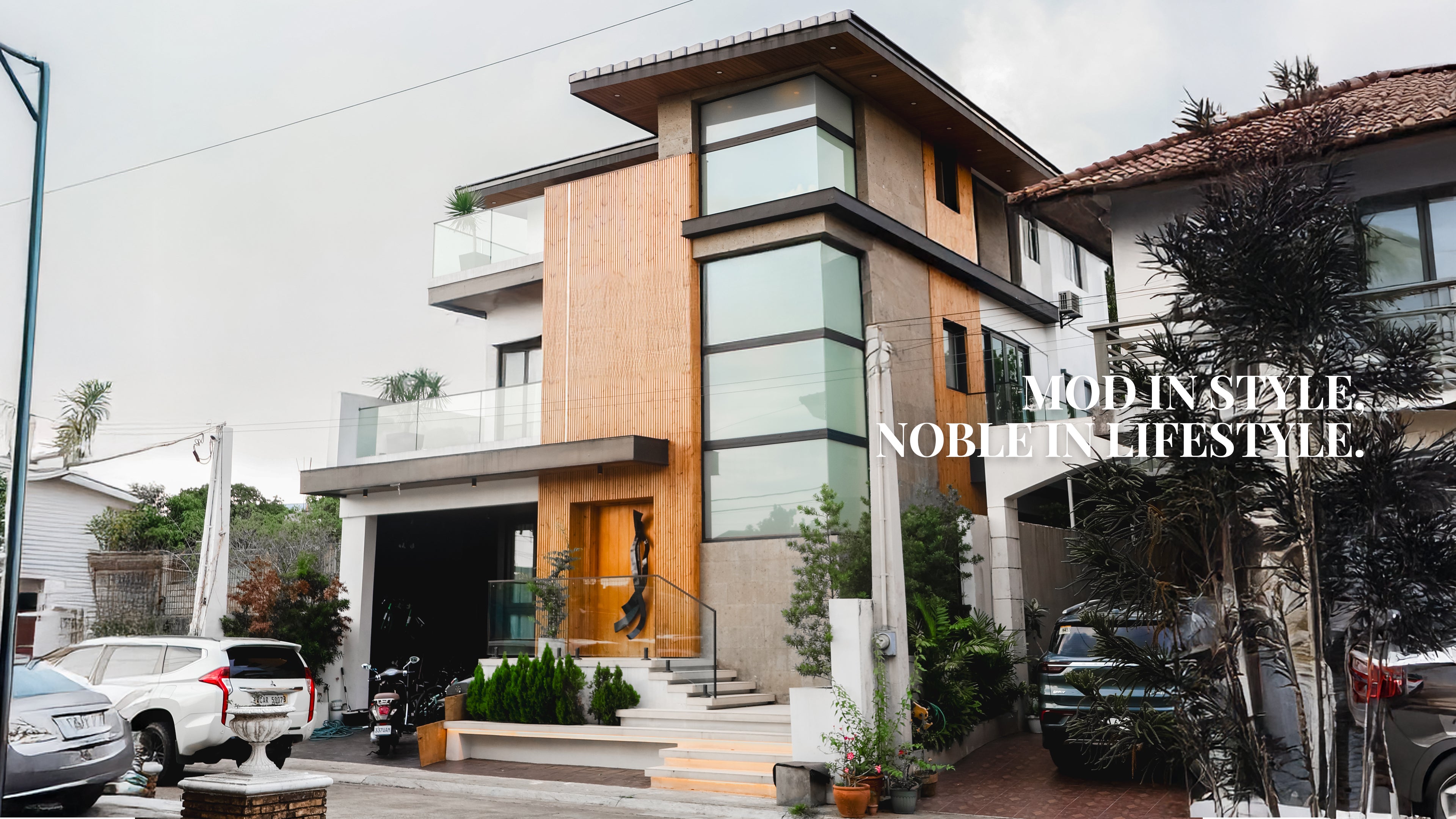 Modern residential house design with wood facade, glass balcony, and contemporary architectural exterior by Mod and Noble Design Studio