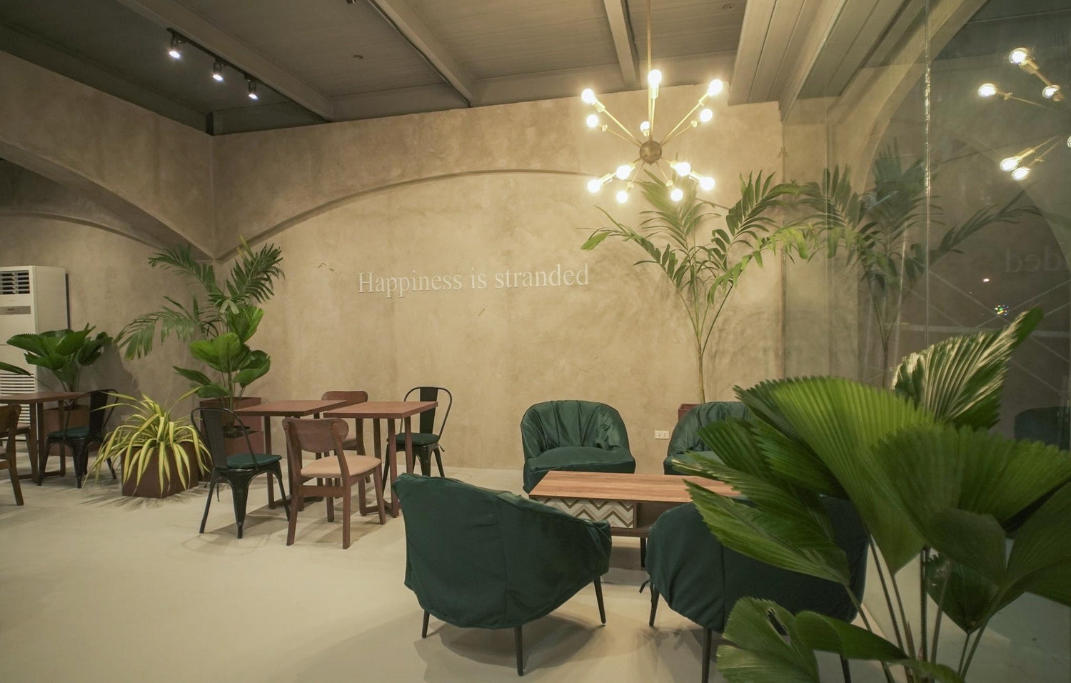 Elegant indoor lounge with plants and the phrase "Happiness is stranded" on the wall.