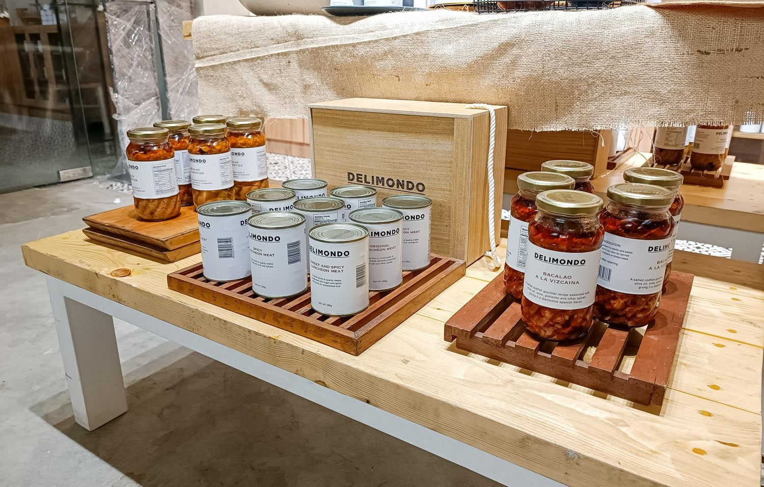 Artisanal food jars displayed on wooden shelves at a gourmet market.