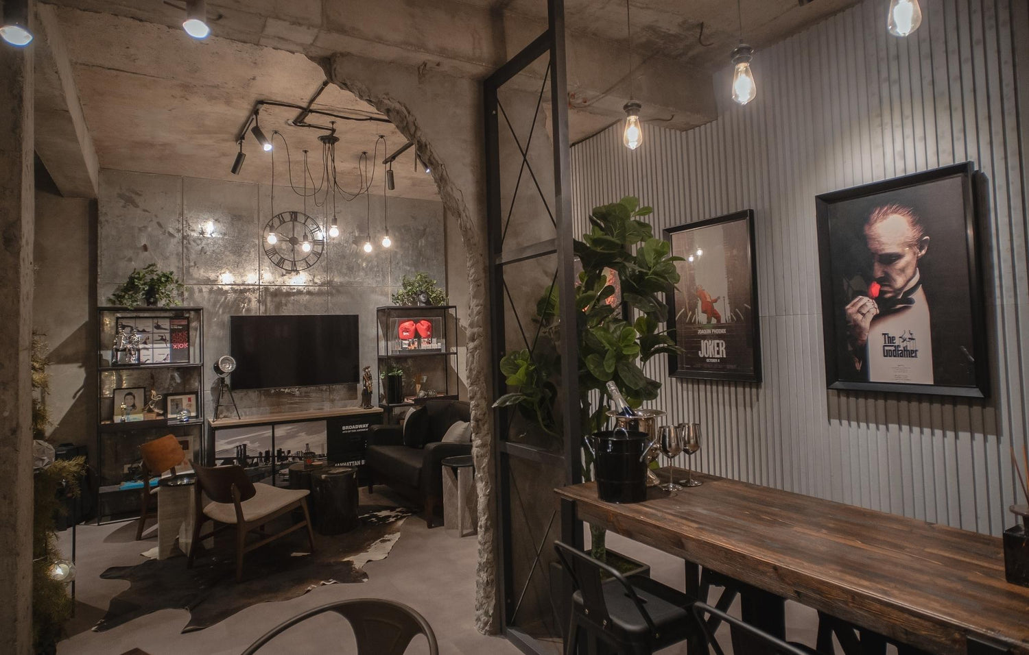 A stylish room with a modern industrial design, featuring exposed concrete, wood furniture, and movie posters.