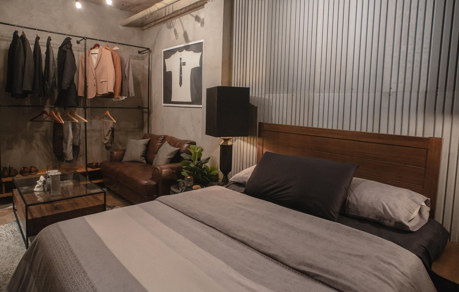 Modern bedroom with bed, open closet with jackets, and leather sofa.