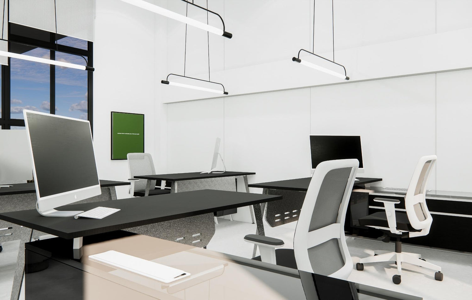 Modern office interior with computers on desks, pendant lights, and a green framed artwork.