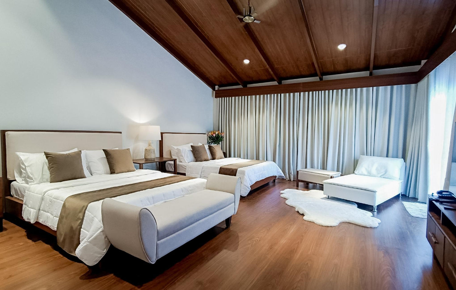 Elegant bedroom with two beds, wooden ceiling, and long curtains.