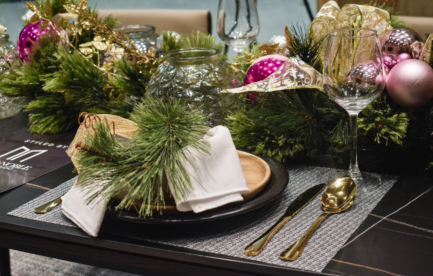  beautifully arranged table setting adorned with Christmas decorations, featuring elegant gold and pink ornaments.