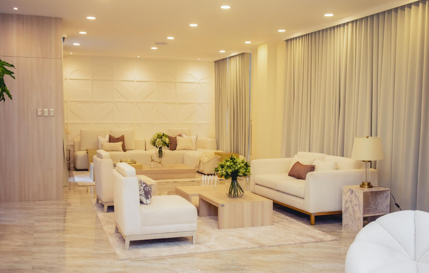 A modern living room adorned with white furniture and a large window that enhances the room's brightness