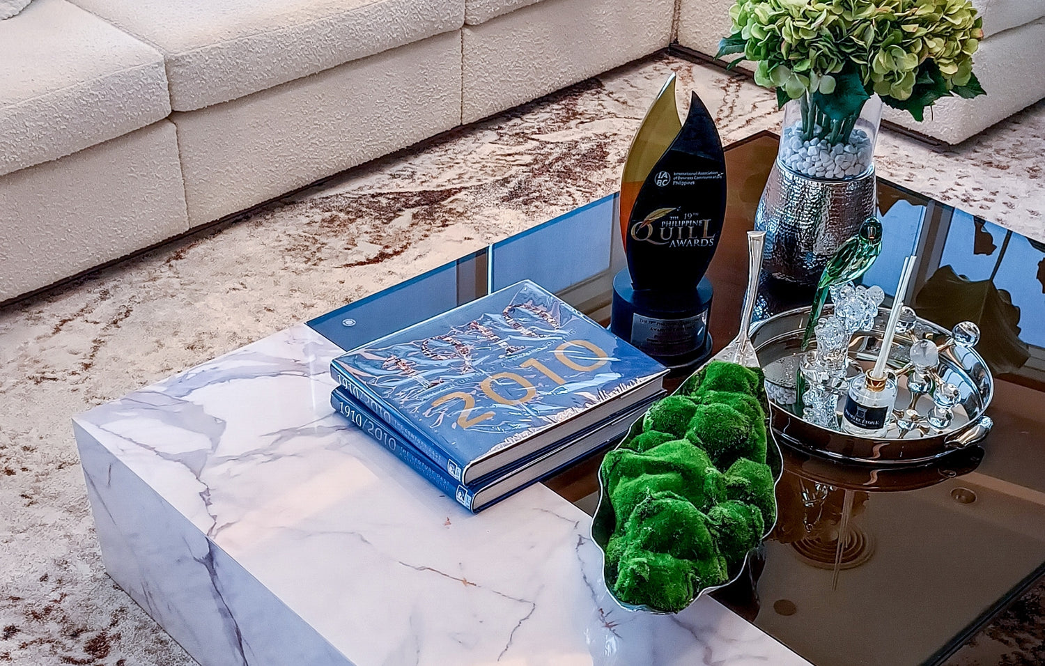 Elegant living room with a marble coffee table displaying books, an award, and decorative items.