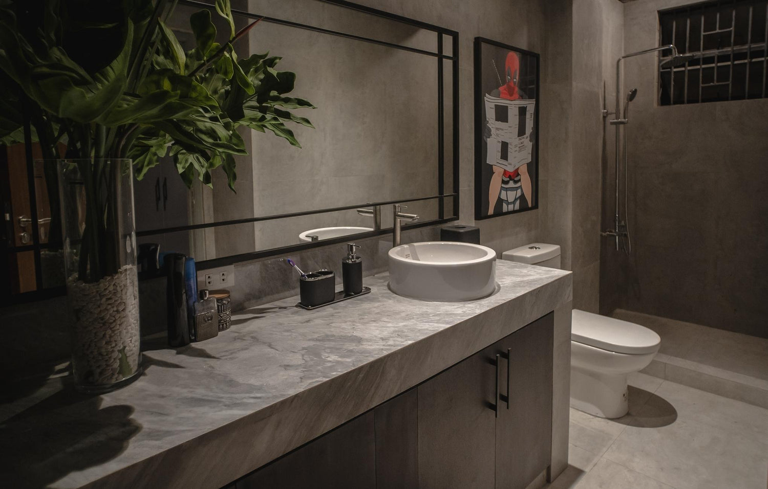 Modern bathroom with a vessel sink, large mirror, artwork on the wall, and a toilet.