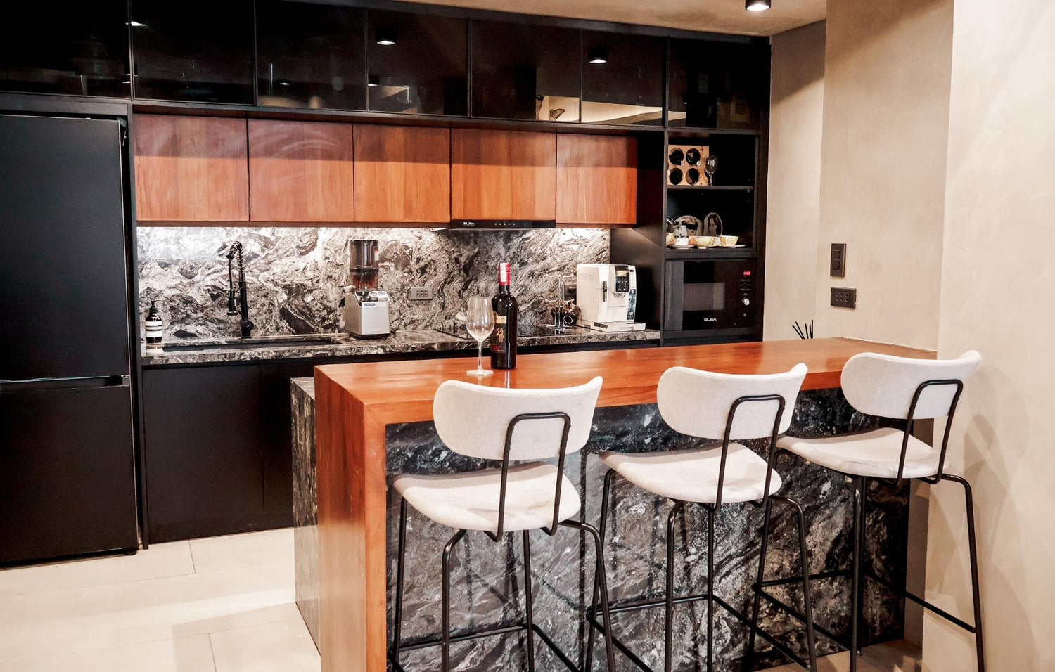 A modern kitchen featuring a sleek marble countertop and stylish bar stools for casual dining.