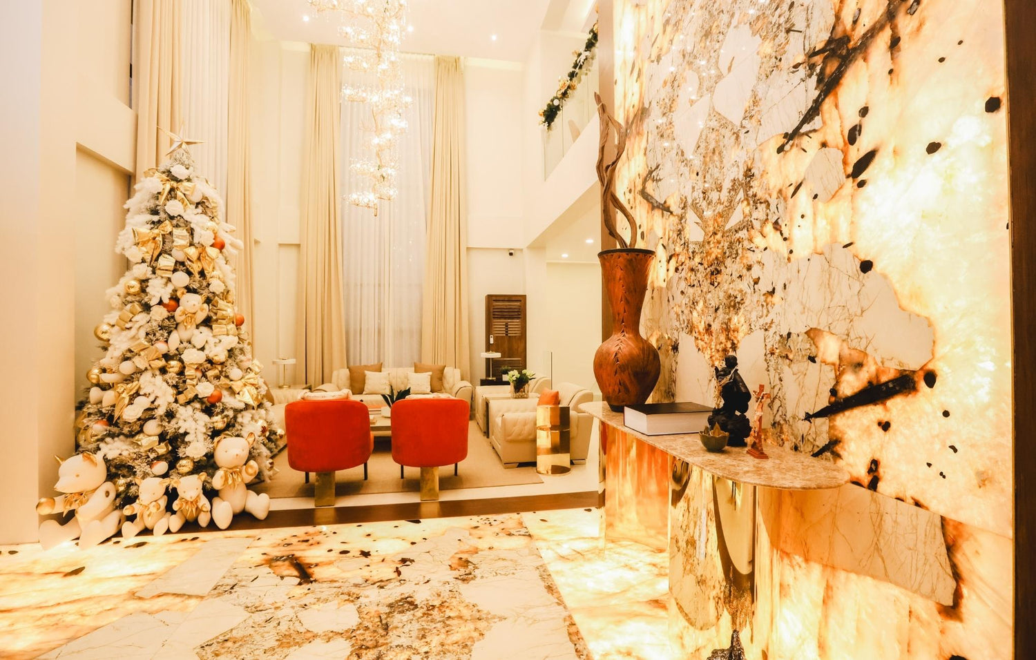 A large marble wall features a beautifully decorated Christmas tree beside an elegant vase, creating a festive atmosphere.
