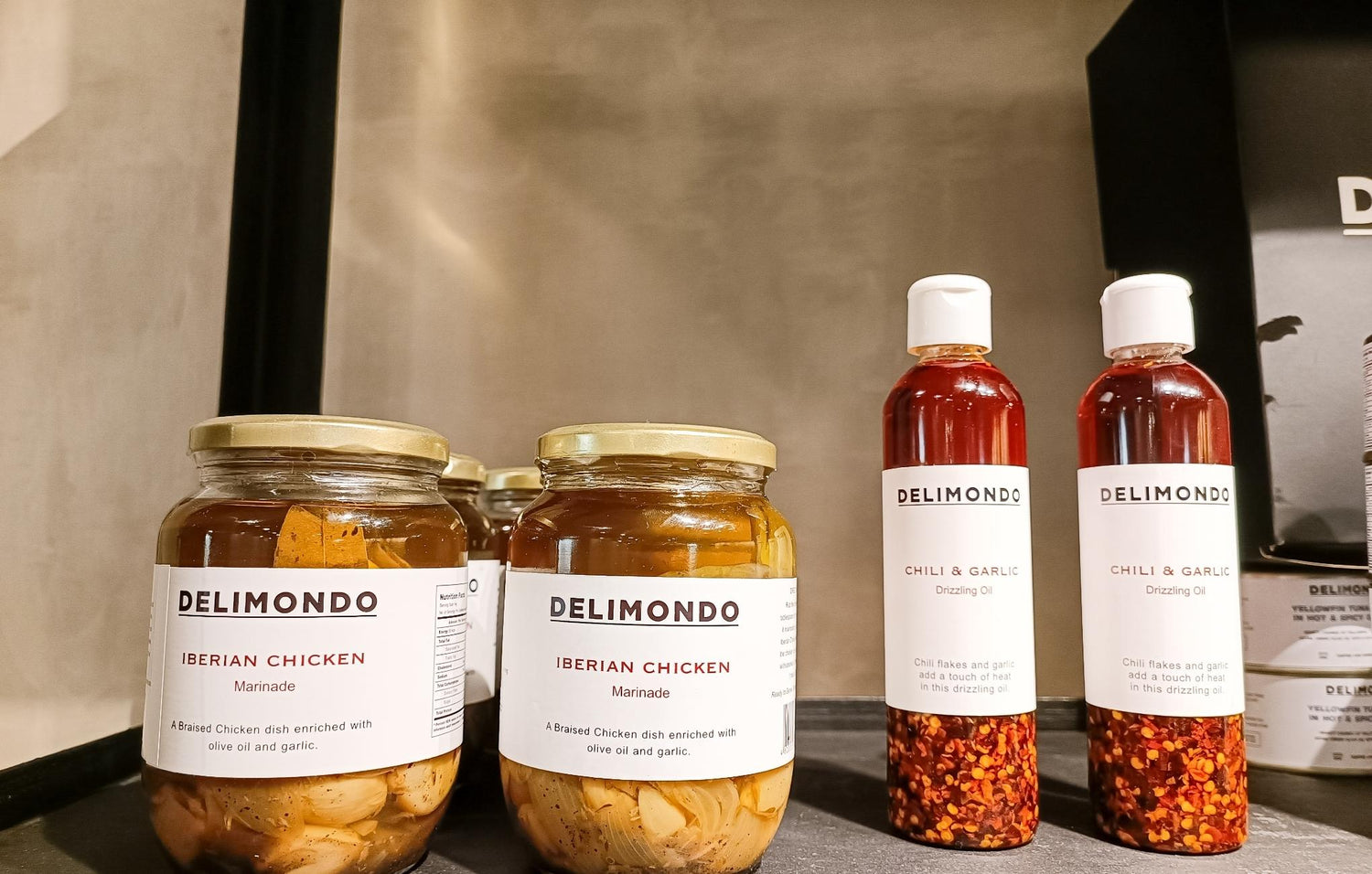 Jars of Iberian Chicken Marinade and bottles of Chili & Garlic Oil on a shelf, labeled DELIMONDO.