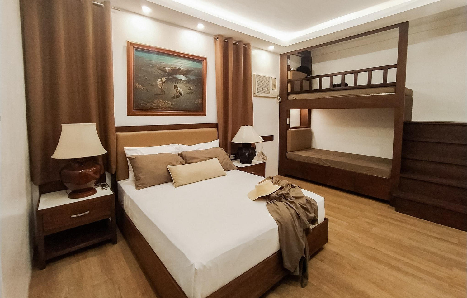 Cozy bedroom with a double bed, bunk beds, lamps, and a painting on the wall.