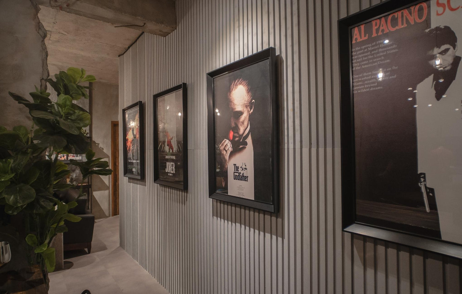 Interior of a room with framed posters on corrugated metal wall and a potted plant.