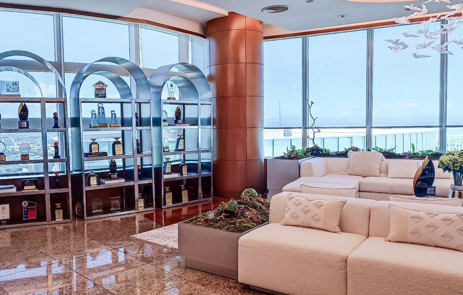 Luxurious lounge interior with elegant cream sofas and a sleek wine display by floor-to-ceiling windows.