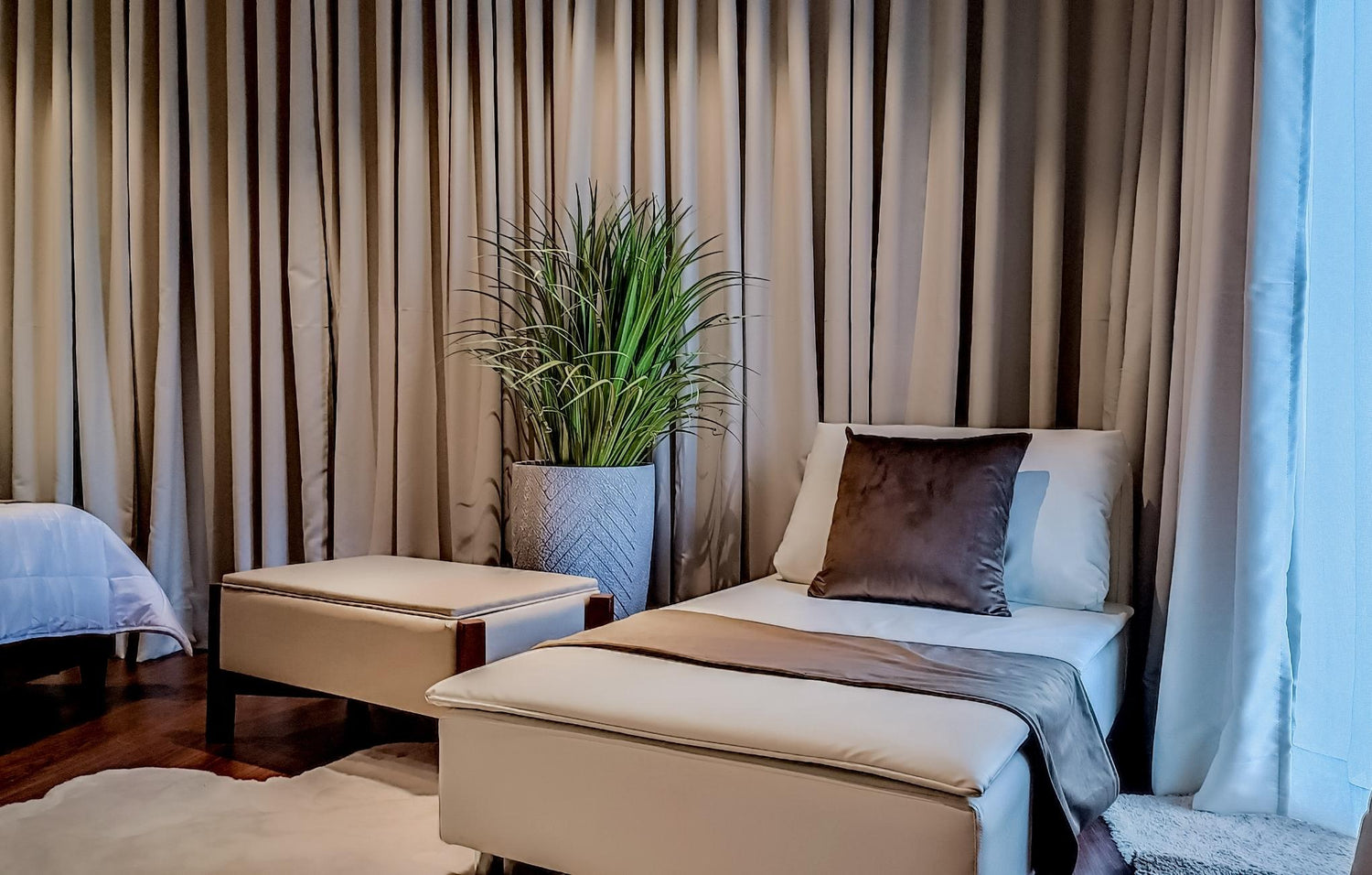 Cozy bedroom featuring a white chair beside a vibrant green plant, creating a serene and inviting atmosphere.