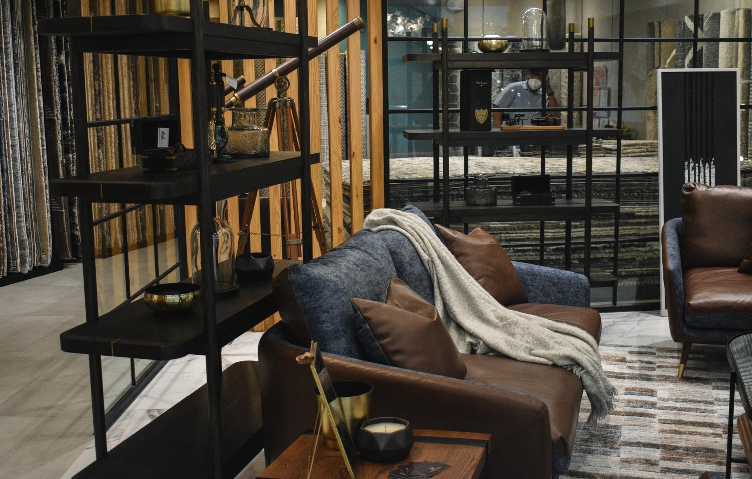 Elegant living room with a brown sofa, armchair, and industrial-style shelving units.