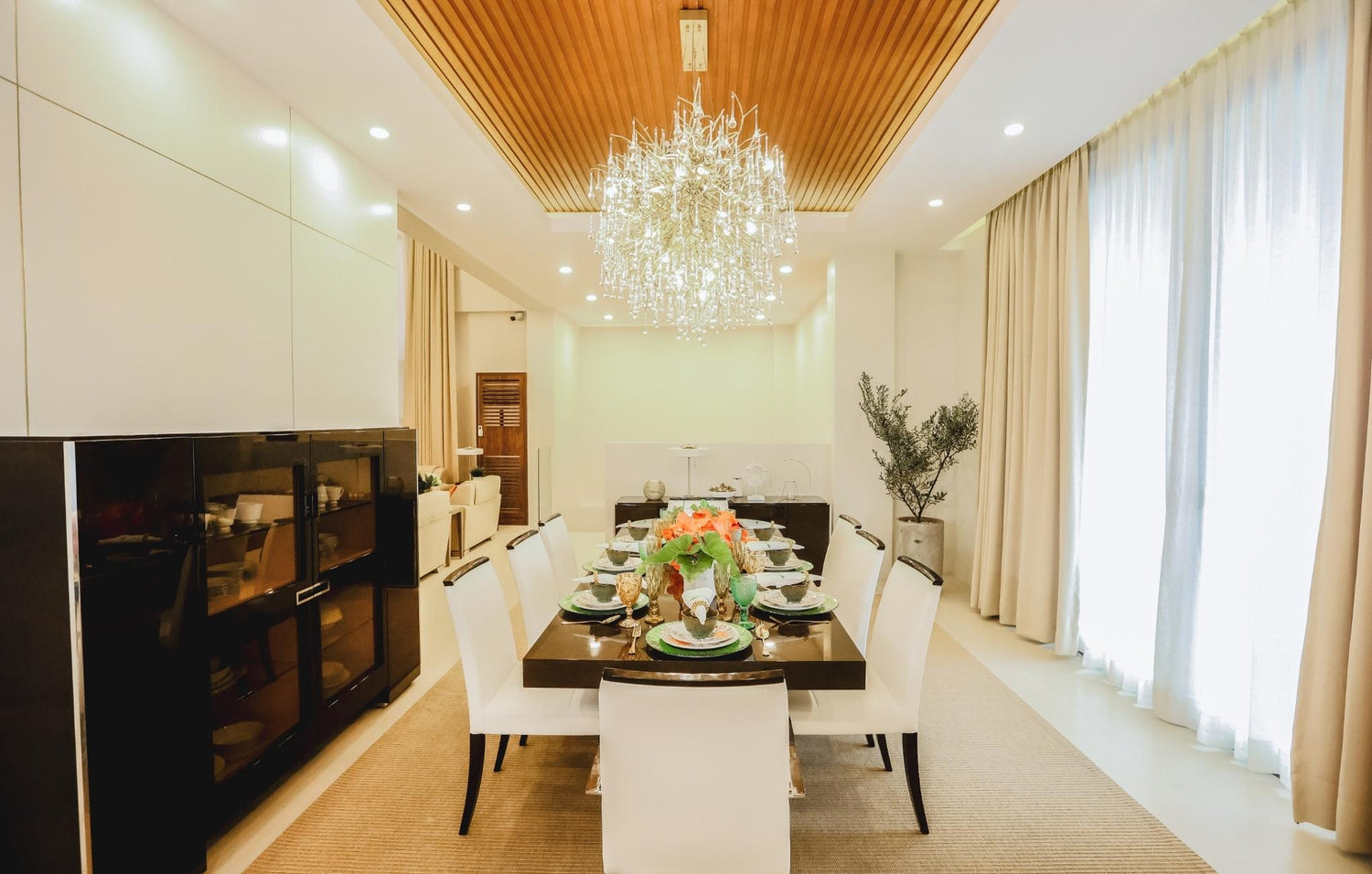 A cozy dining room featuring an elegant chandelier hanging above a beautifully set table.