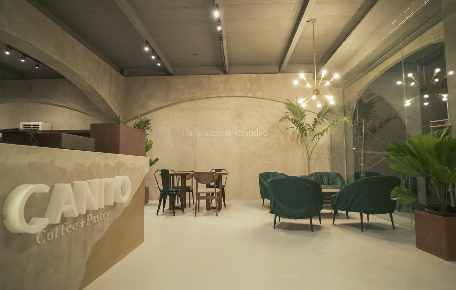 Modern cafe interior with comfortable seating, dim lighting, and a statement wall saying "Happiness is stranded."