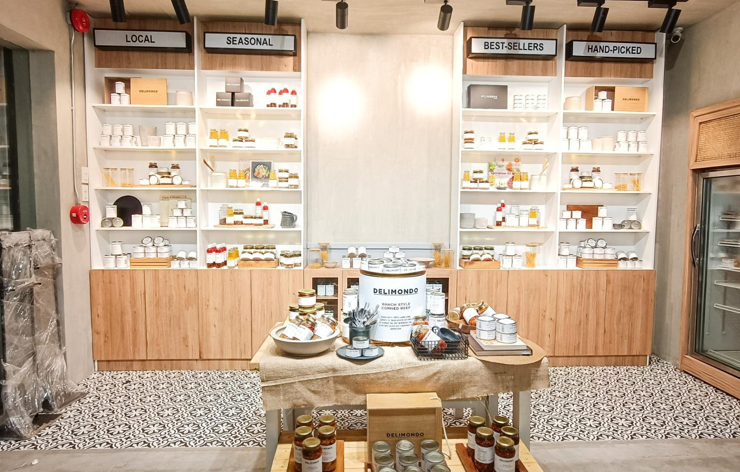 A modern, well-lit boutique store with shelves labeled "Local," "Seasonal," "Best-Sellers," and "Hand-Picked."