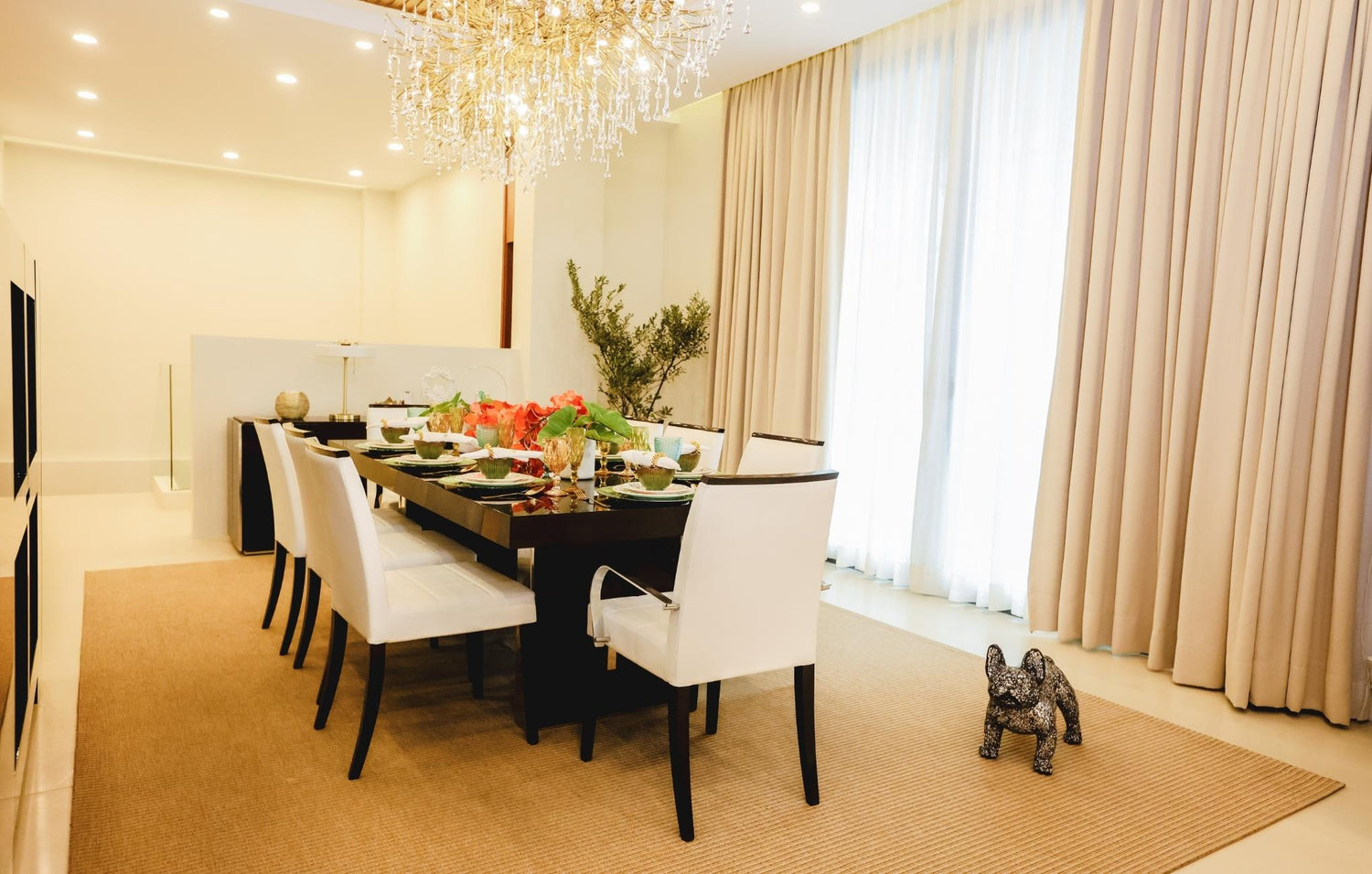  A cozy dining room featuring an elegant chandelier hanging above a beautifully set table.