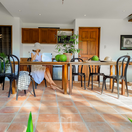 IDr. Jullienne Iris C. Taguinod, PIID, sits at a kitchen table with a laptop, wearing a hat and surrounded by green decor, effortlessly combining work and style.