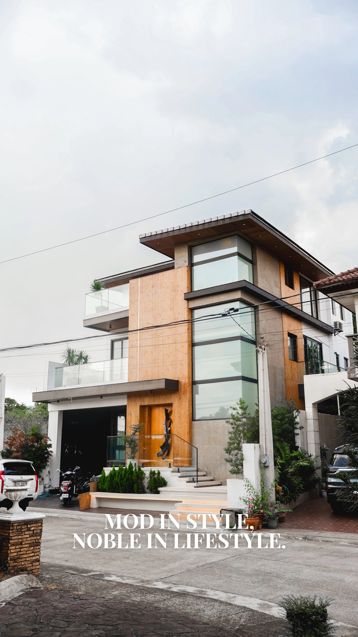 Modern residential house design with wood facade, glass balcony, and contemporary architectural exterior by Mod and Noble Design Studio